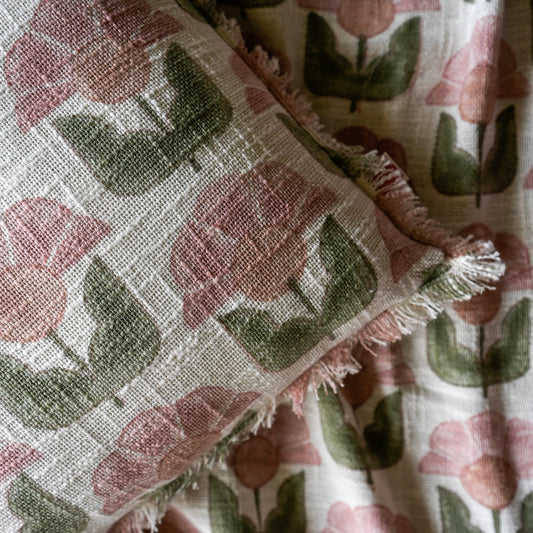 Floral patterned fabric with pink flowers and green leaves on a textured background
