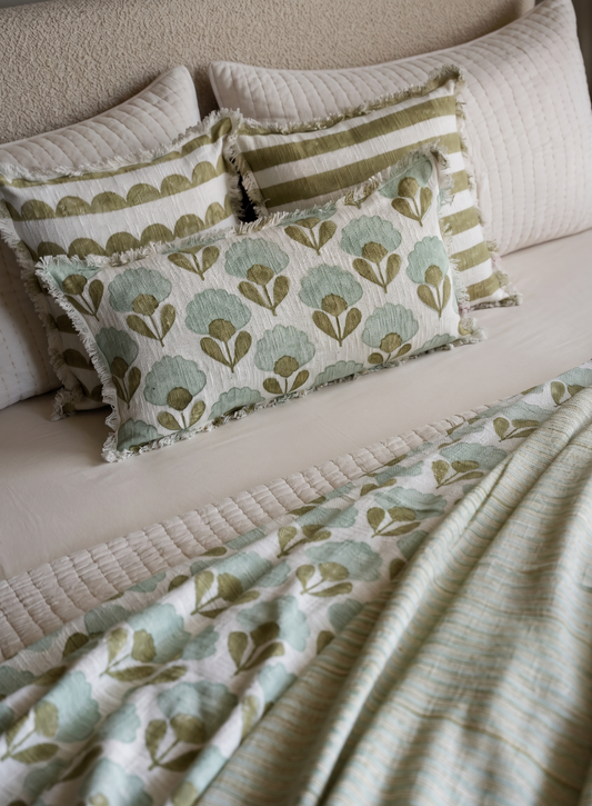 Bed with patterned green and beige bedding and pillows.