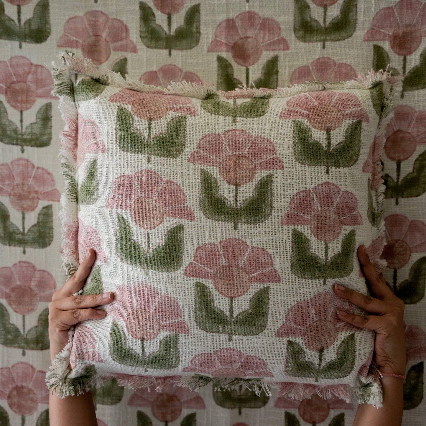 Person holding a fabric with pink and green floral pattern