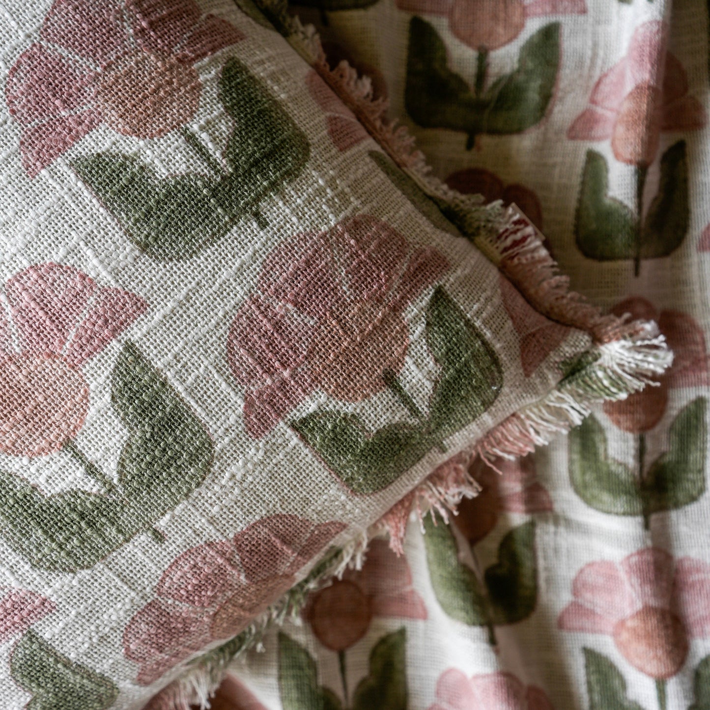 Floral patterned fabric with pink flowers and green leaves on a textured background