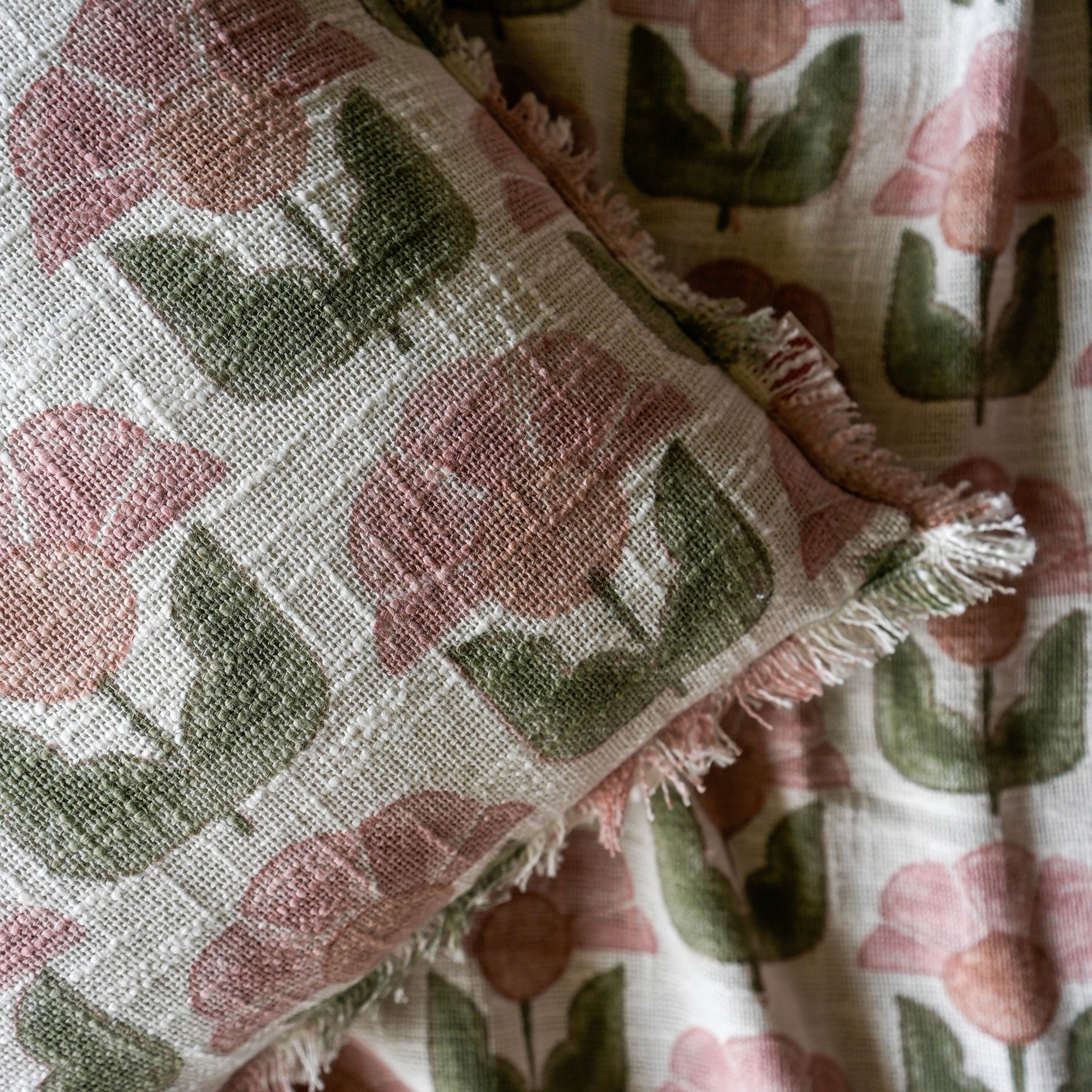 Floral patterned fabric with pink flowers and green leaves on a textured background