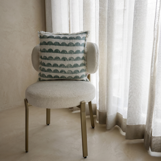 Chair with a patterned pillow in front of a curtain
