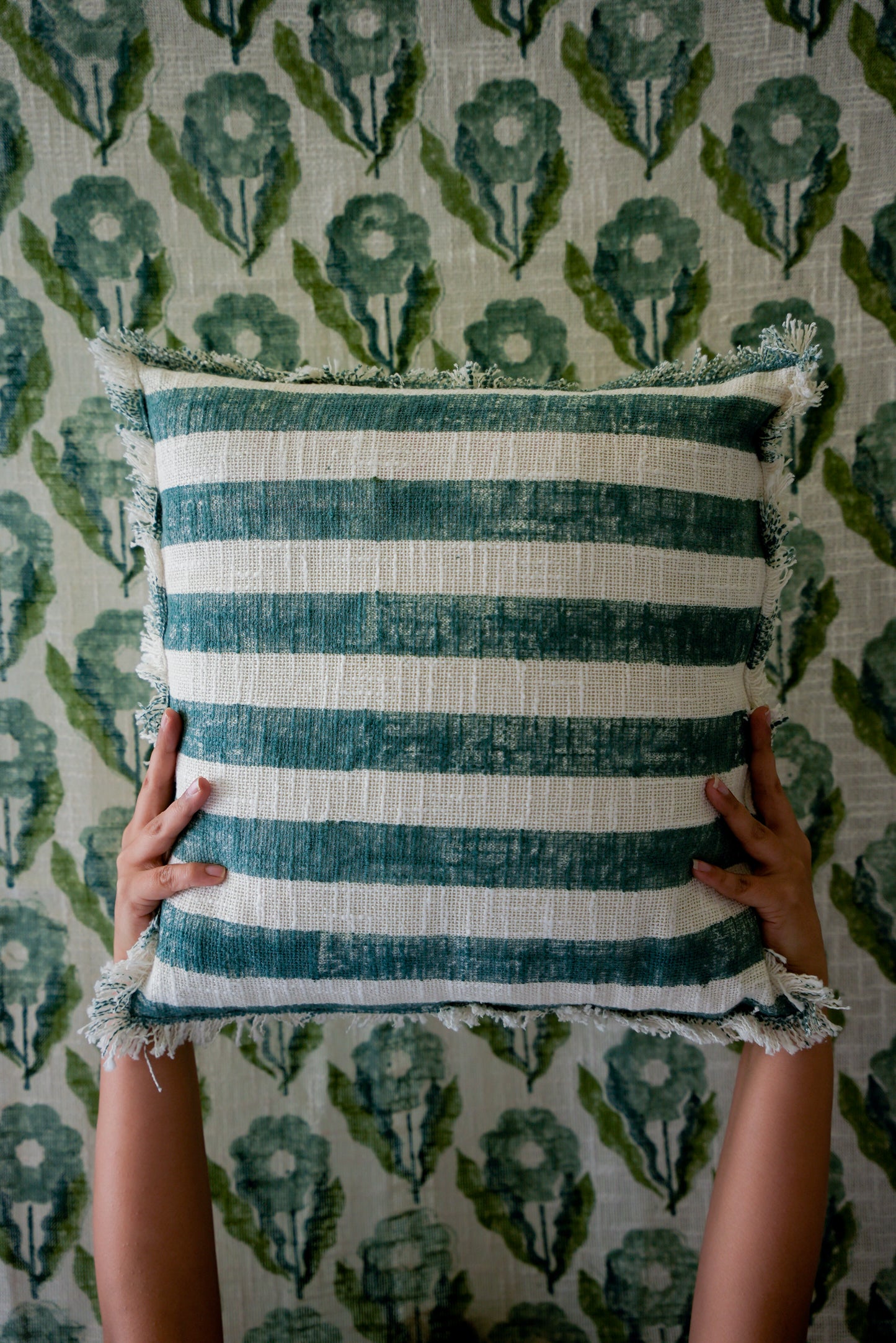 Striped pillow held against a patterned wall