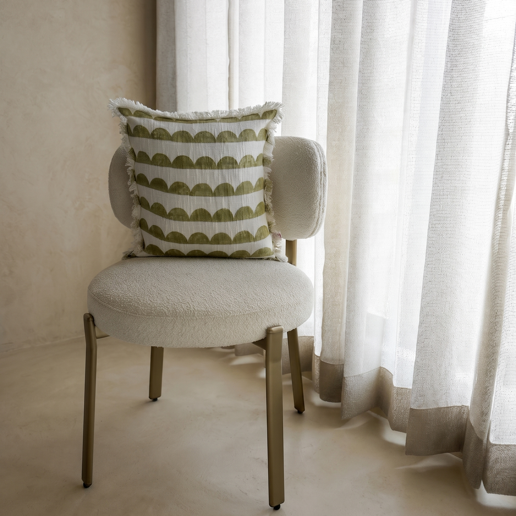 Chair with a decorative pillow in front of sheer curtains