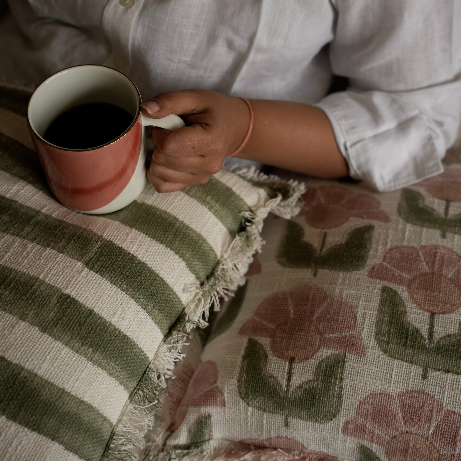 block printed striped cushion on womans lap having cofee