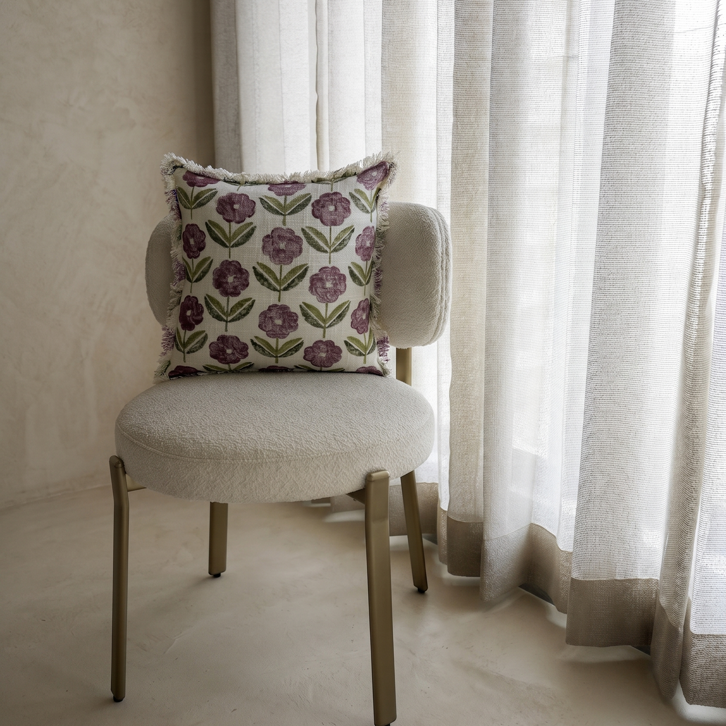 Chair with a decorative pillow in front of sheer curtains