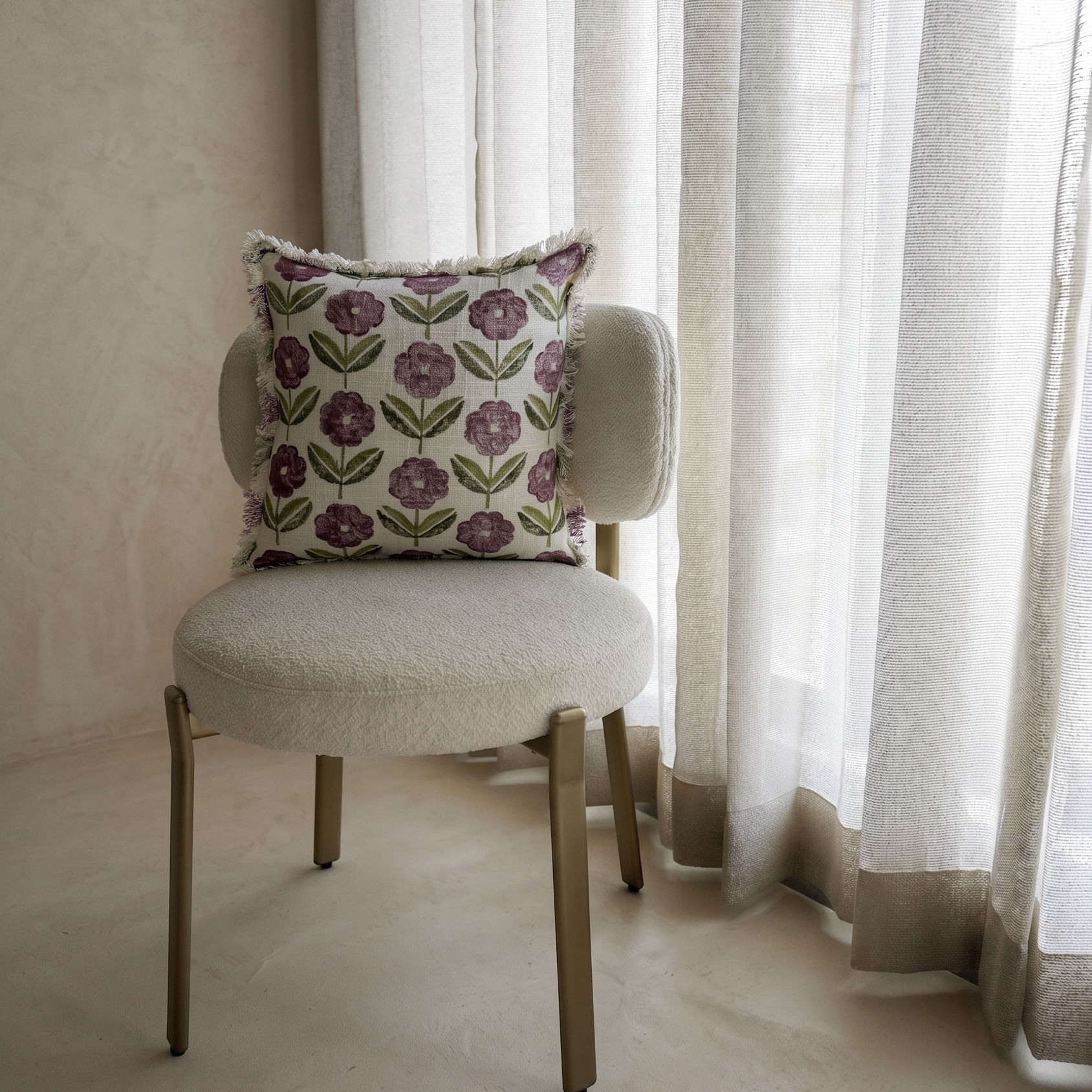 Chair with a decorative pillow in front of sheer curtains