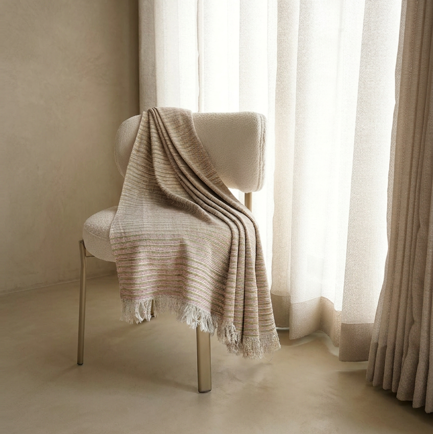 Folded beige fabric on a metal rod against a neutral wall.