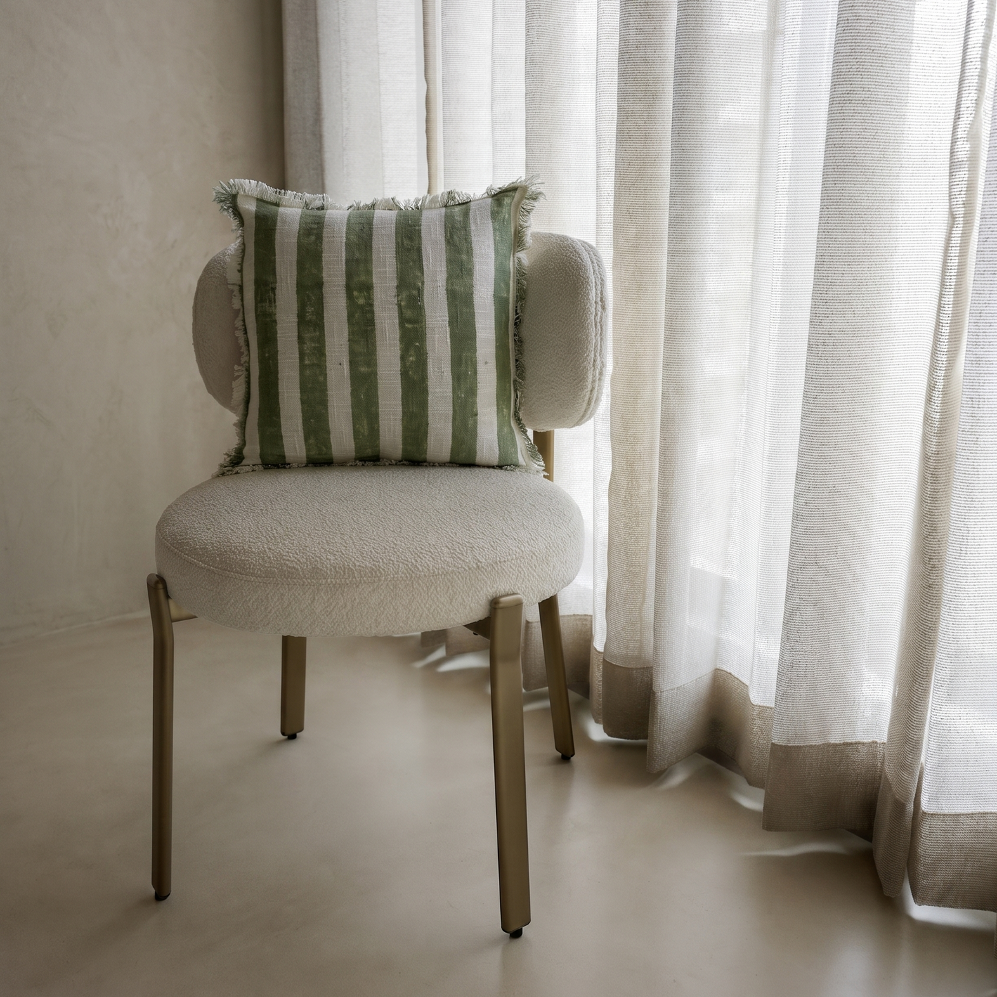 Chair with a striped pillow in front of sheer curtains