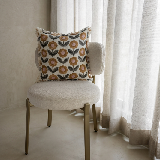 Decorative pillow on a chair with curtains in the background