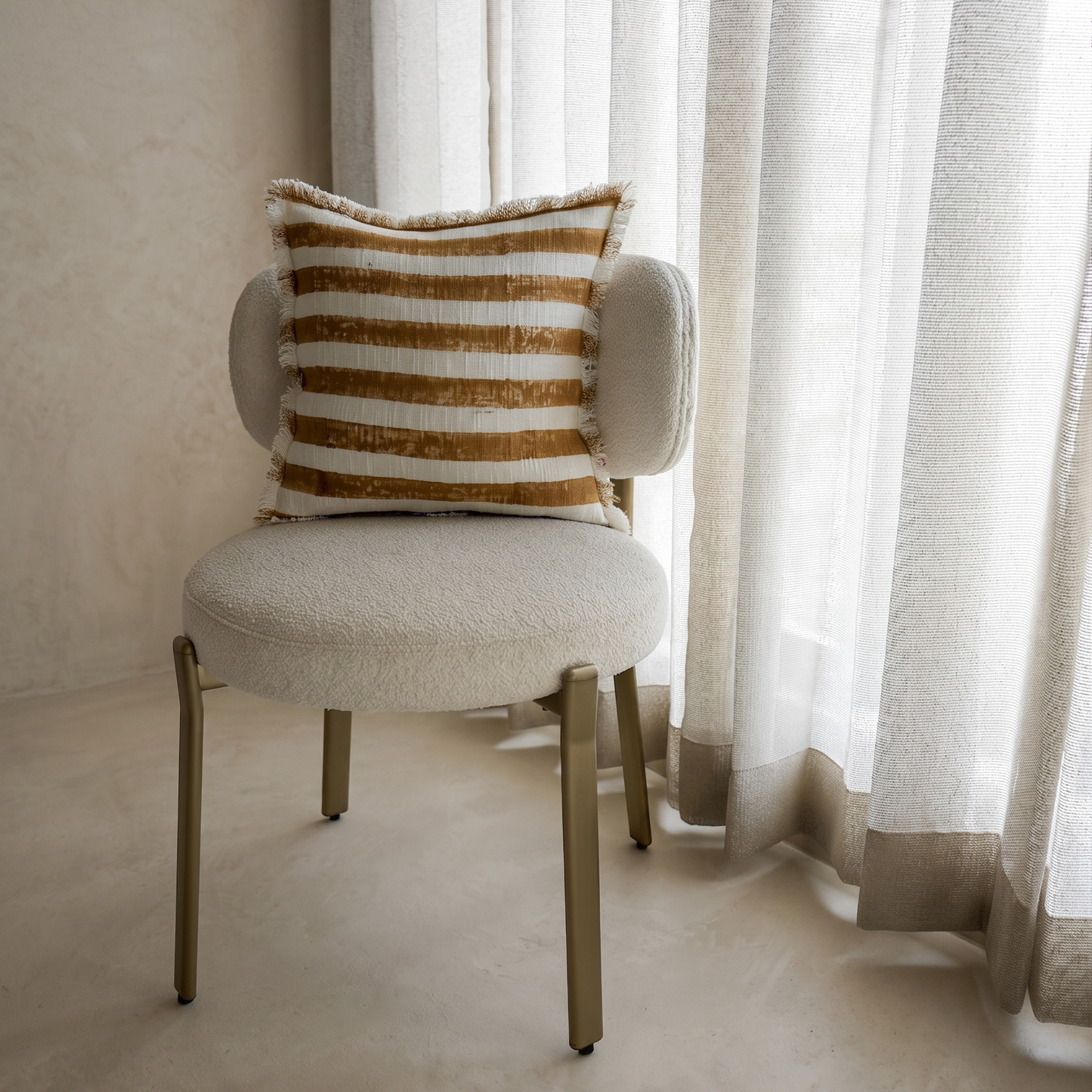 Chair with a striped pillow in a room with light curtains