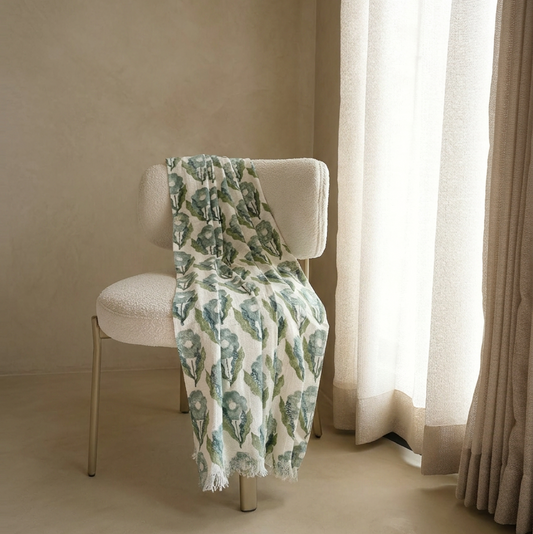 Folded patterned fabric on a metal rod against a beige wall.